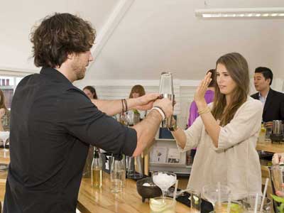 Mixologist showing a woman how to make a cocktail