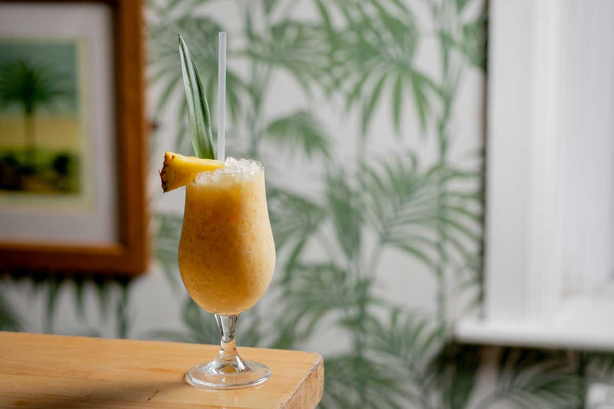 Cocktail on a bar top in a room with palm tree wallpaper
