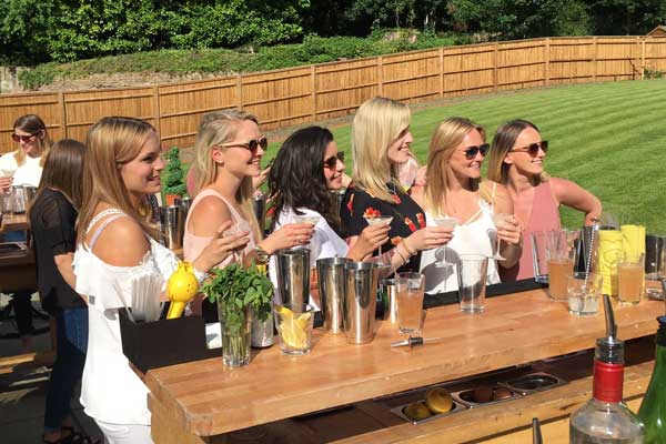 Group of ladies stood round a cocktail bar set up in a back garden