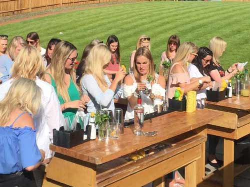 Group of women making cocktails on mobile bars set up in a back garden for a recent hen party