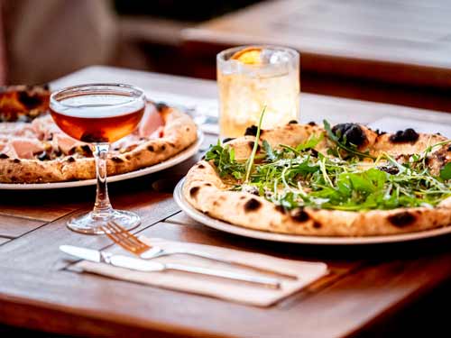 Two fresh pizzas and two cocktails on a table